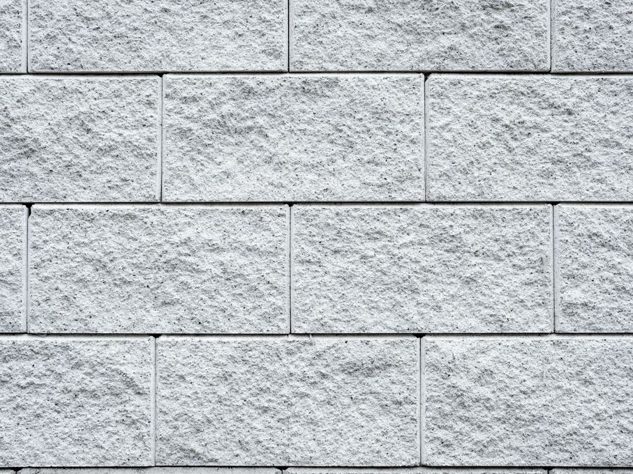 Close-up of a gray brick wall with textured surfaces and visible mortar lines.
