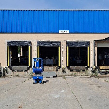 Warehouse loading docks with blue lift in front. Dock 6 sign visible.