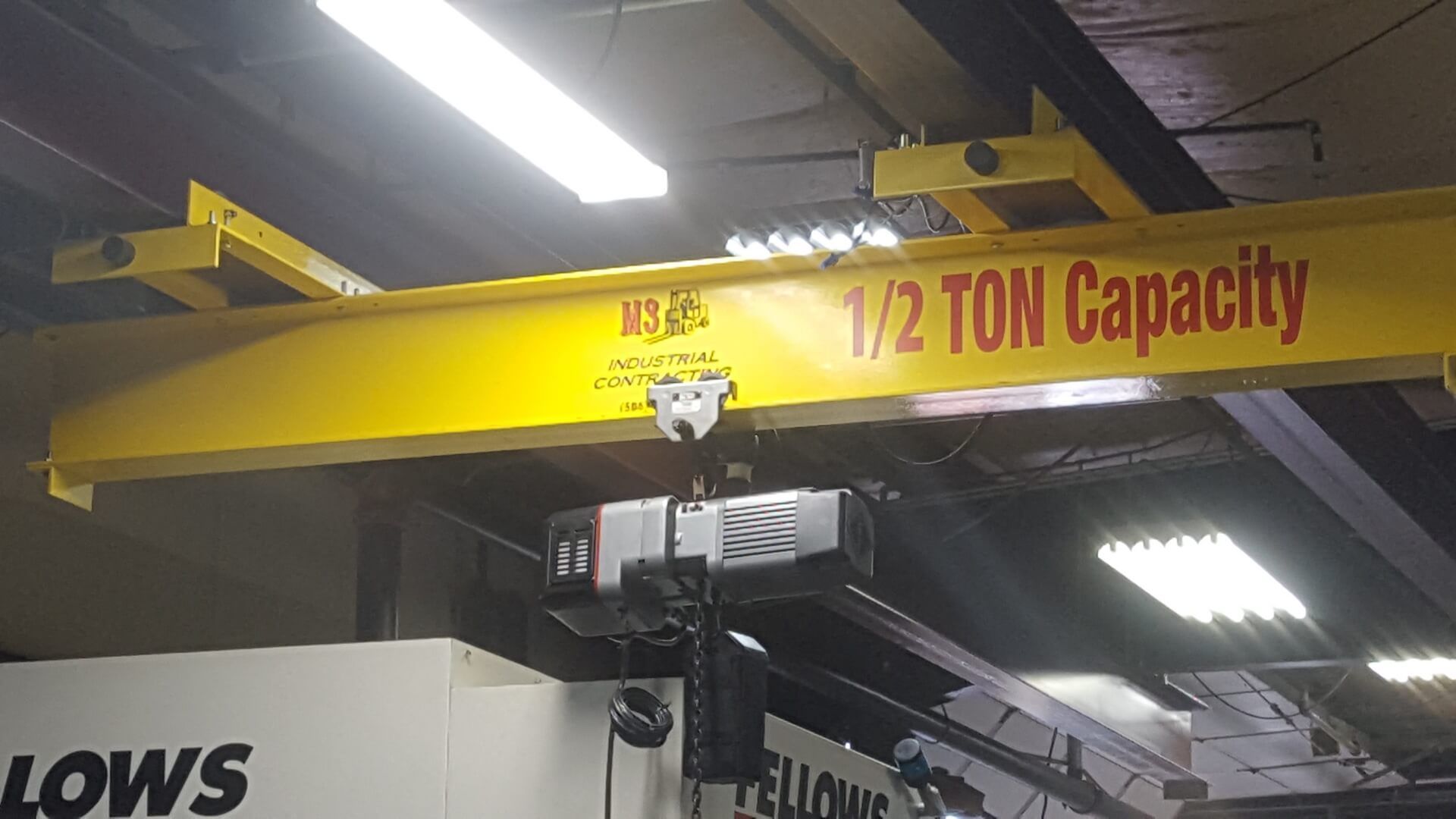 Yellow overhead crane with 1/2 TON capacity sign in a factory.