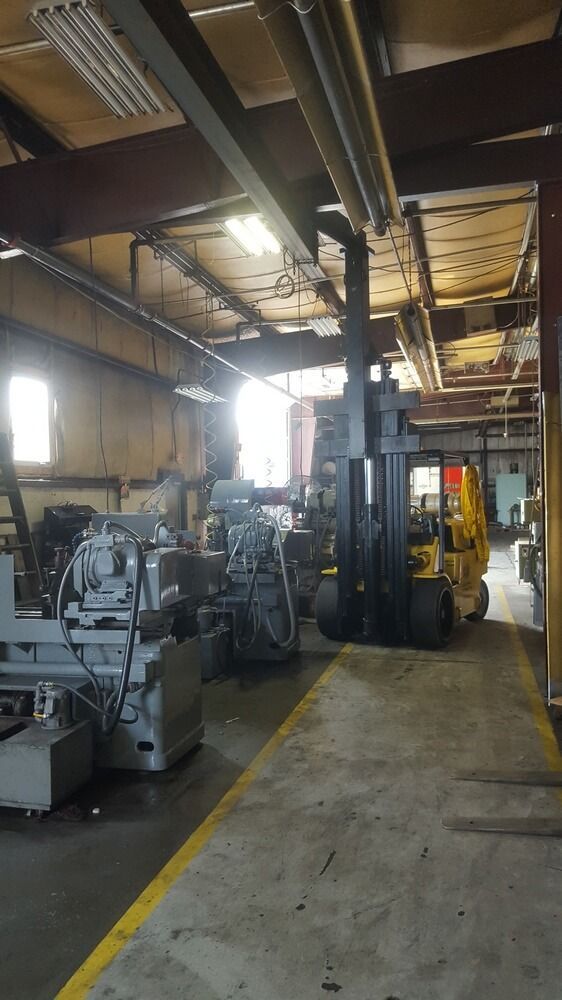 Forklift in a dimly lit industrial space, near machinery.