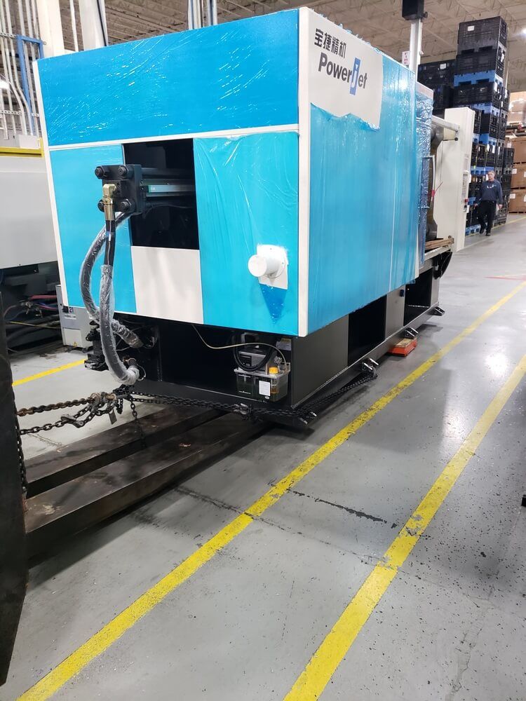 Large blue and black industrial machine on a forklift in a warehouse.