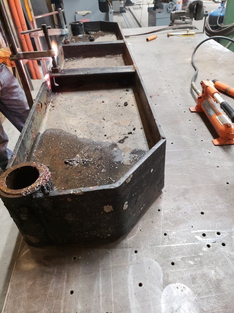A person welds a metal structure on a workbench in a workshop.