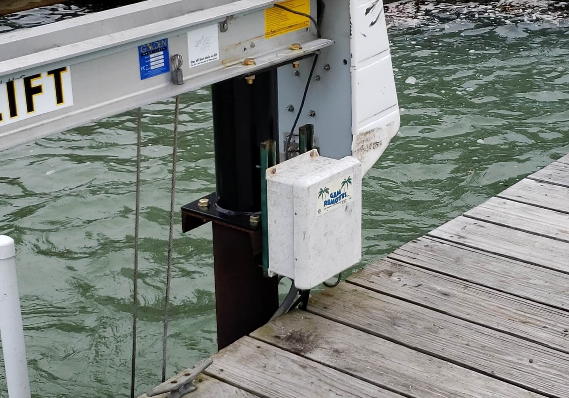 Boat lift machinery attached to a wooden dock over water.