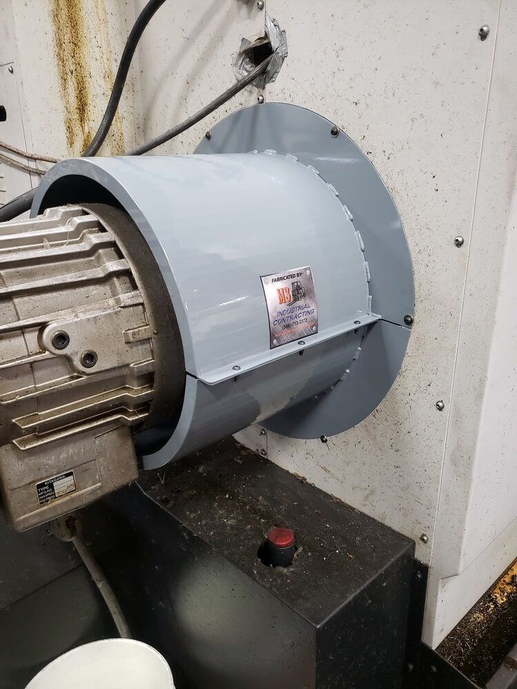 A grey motor fan housing is attached to a machine.