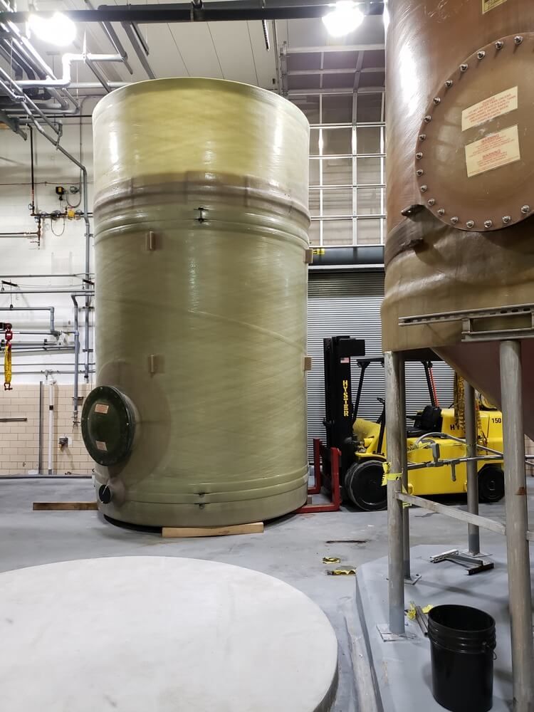 Large cylindrical industrial tank with a yellow forklift in a warehouse setting.