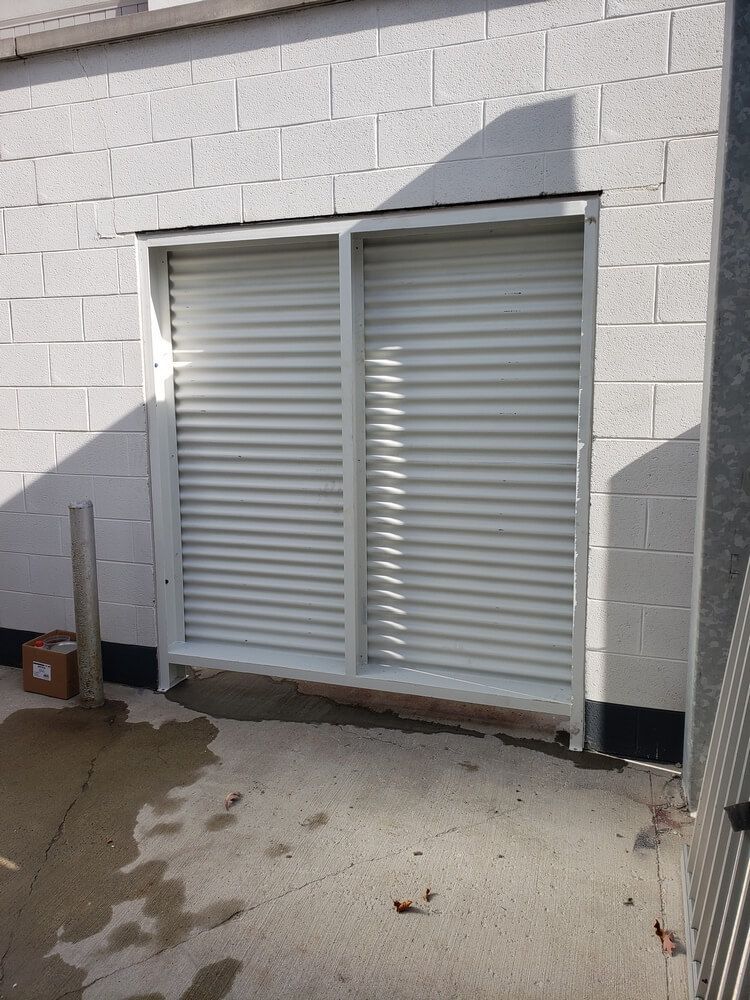 White metal security shutters set in a white brick wall.