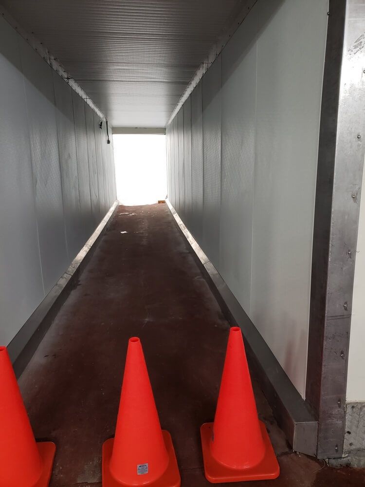 Interior of a tunnel with bright light at the end. Orange cones line the floor.