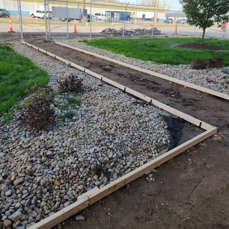 Pathway under construction with wooden borders, gravel, and exposed soil.