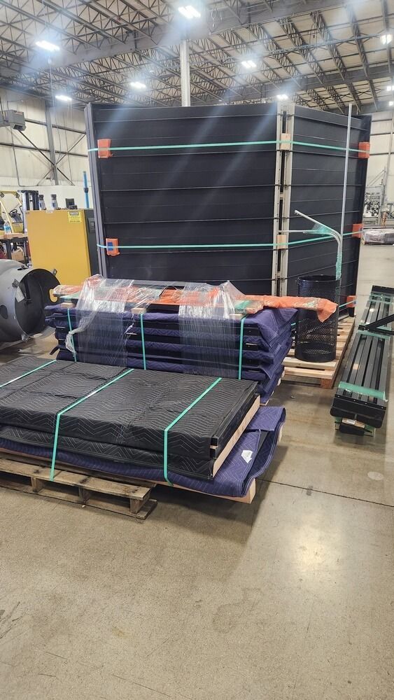Pallets of black material stacked in a warehouse, secured with straps.