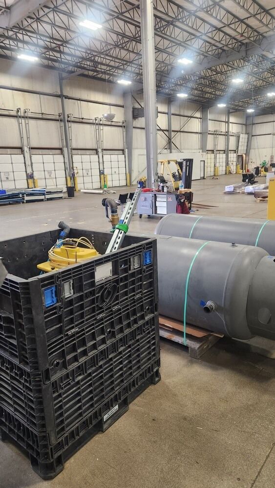 Large warehouse interior with equipment in foreground, two large tanks on a pallet.