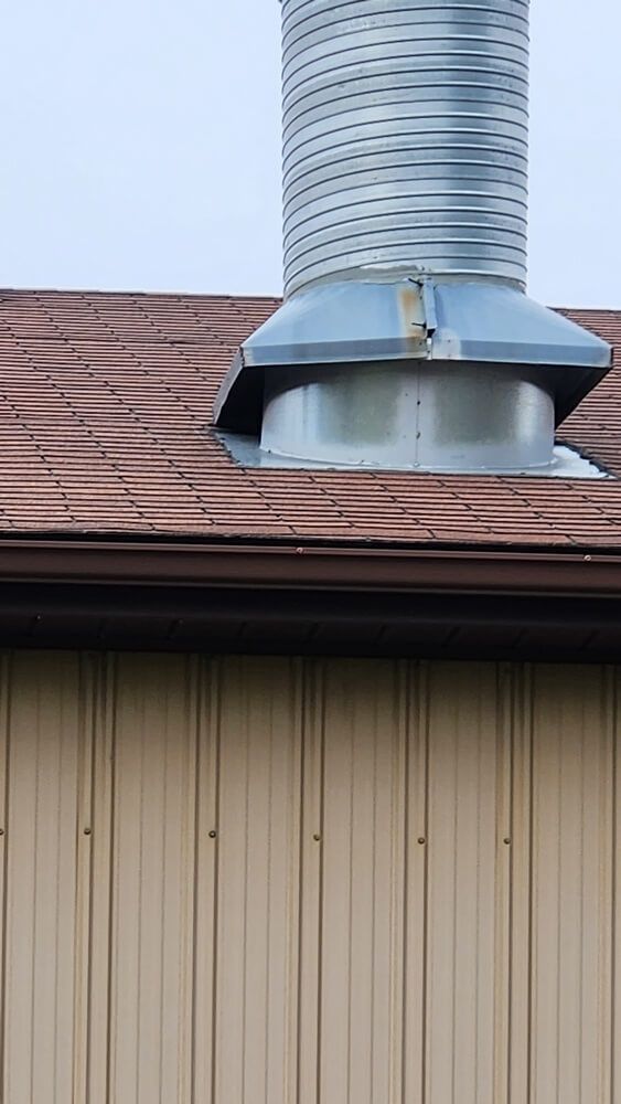 Metal roof with vent pipe and beige building siding.