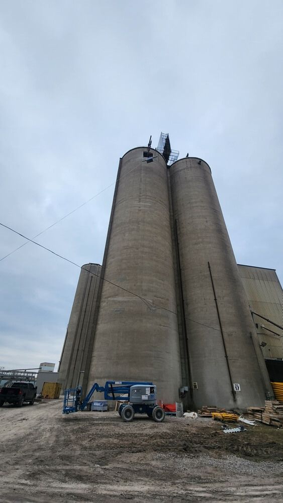 Tall concrete silos with machinery, under overcast sky.