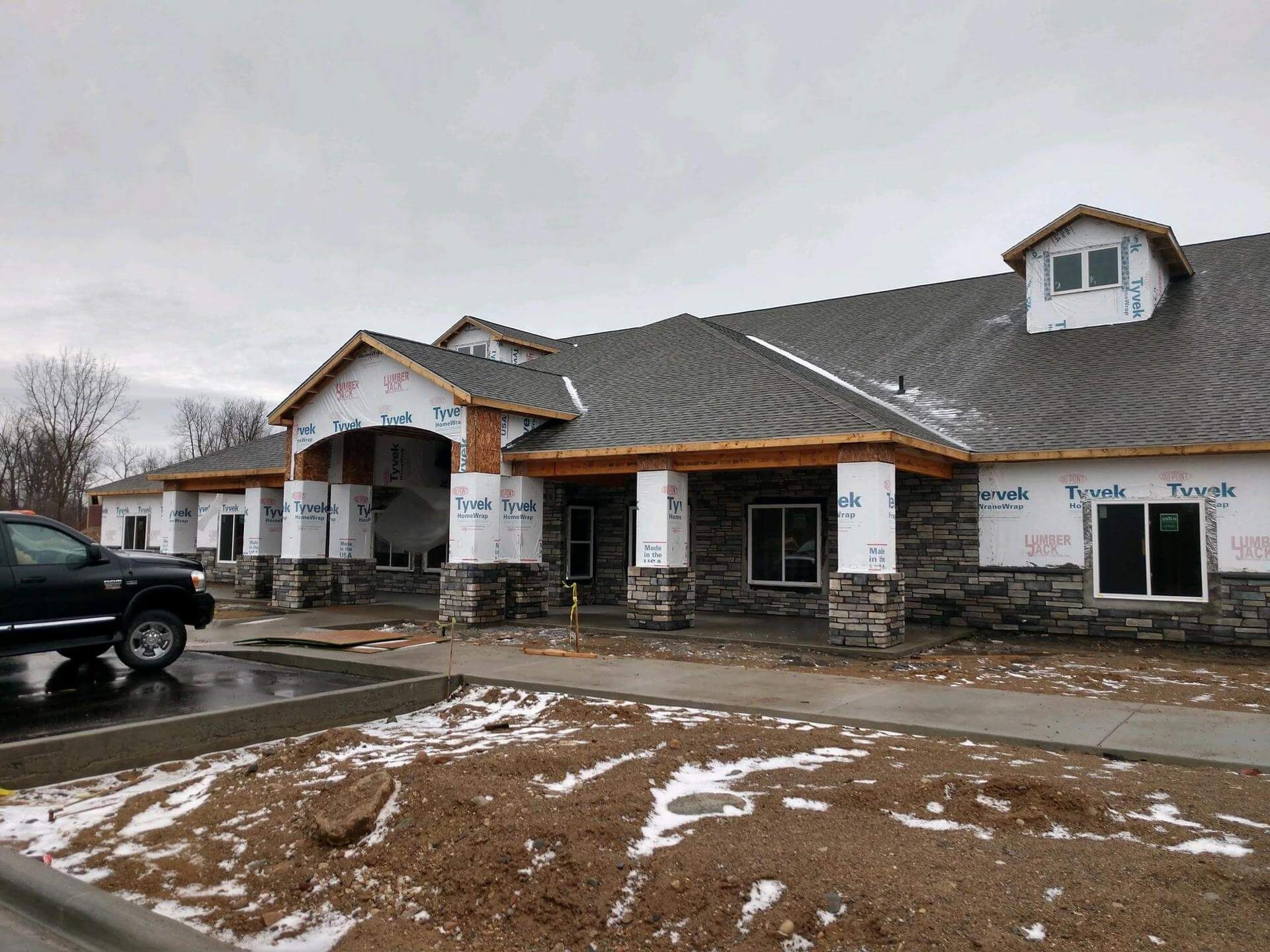 Building under construction with stone facade, under gray sky.