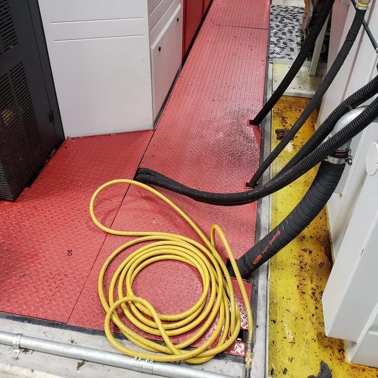 Yellow electrical cord coiled on a red floor near machinery with black hoses.