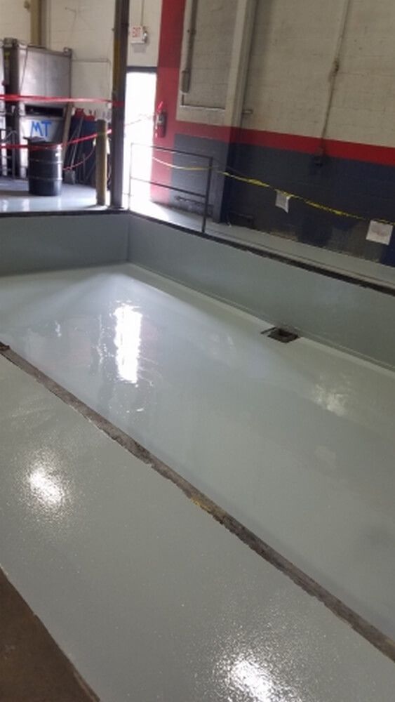 Light gray concrete floor in a workshop, possibly newly coated. A drain is visible.