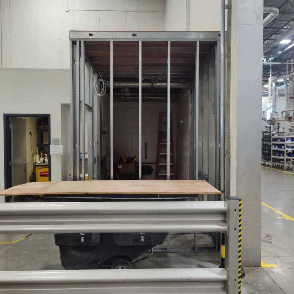 Platform lift in a warehouse, with a piece of wood on it.