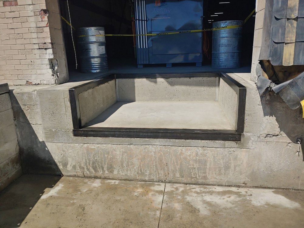 Concrete loading dock with recessed area and black rubber bumpers.