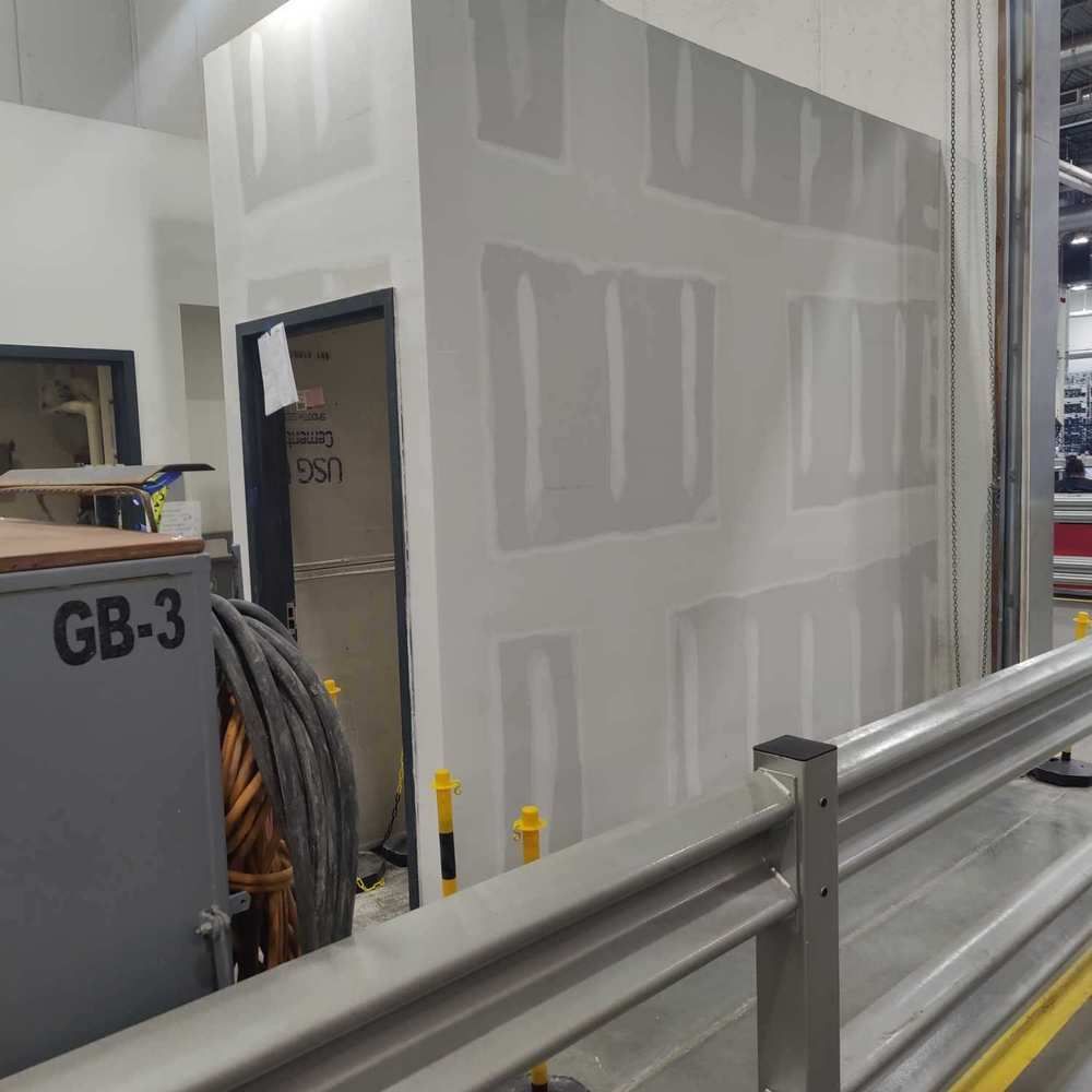 A partially constructed wall with a door inside a building. A metal railing is in the foreground.