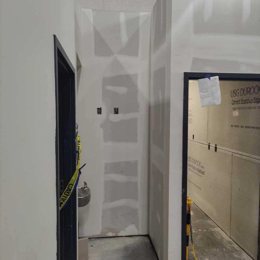 Interior hallway with unfinished drywall, doorways, and caution tape.