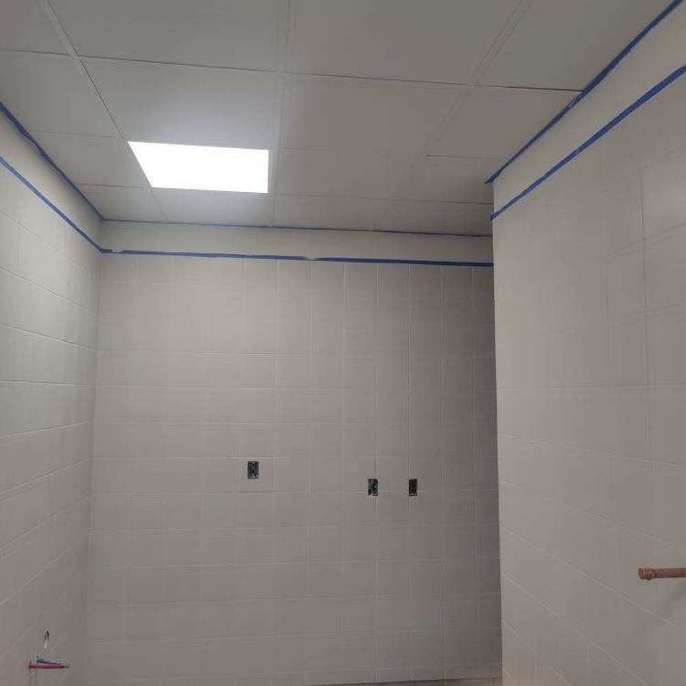 Bathroom interior, white walls, blue tape along edges, ceiling with a light fixture.