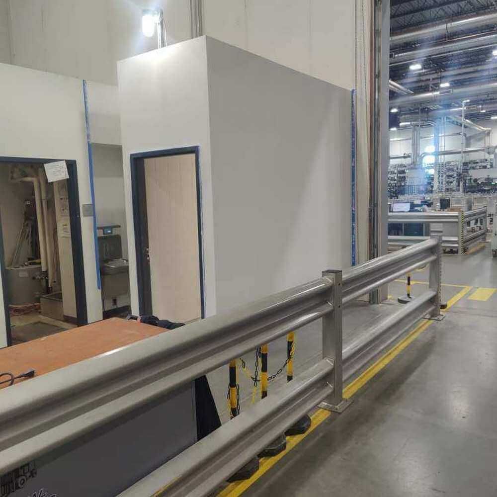 White industrial building interior with safety railing, doors, and machinery.