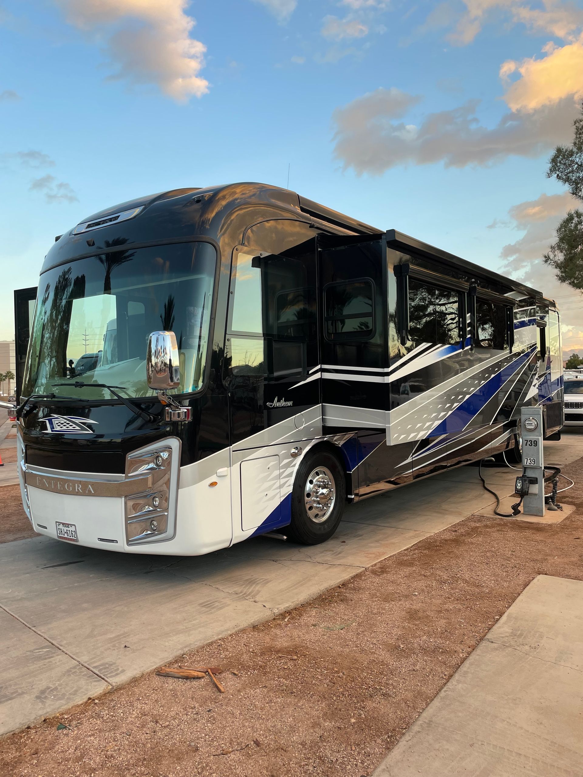 A large white and blue rv is parked on the side of the road.