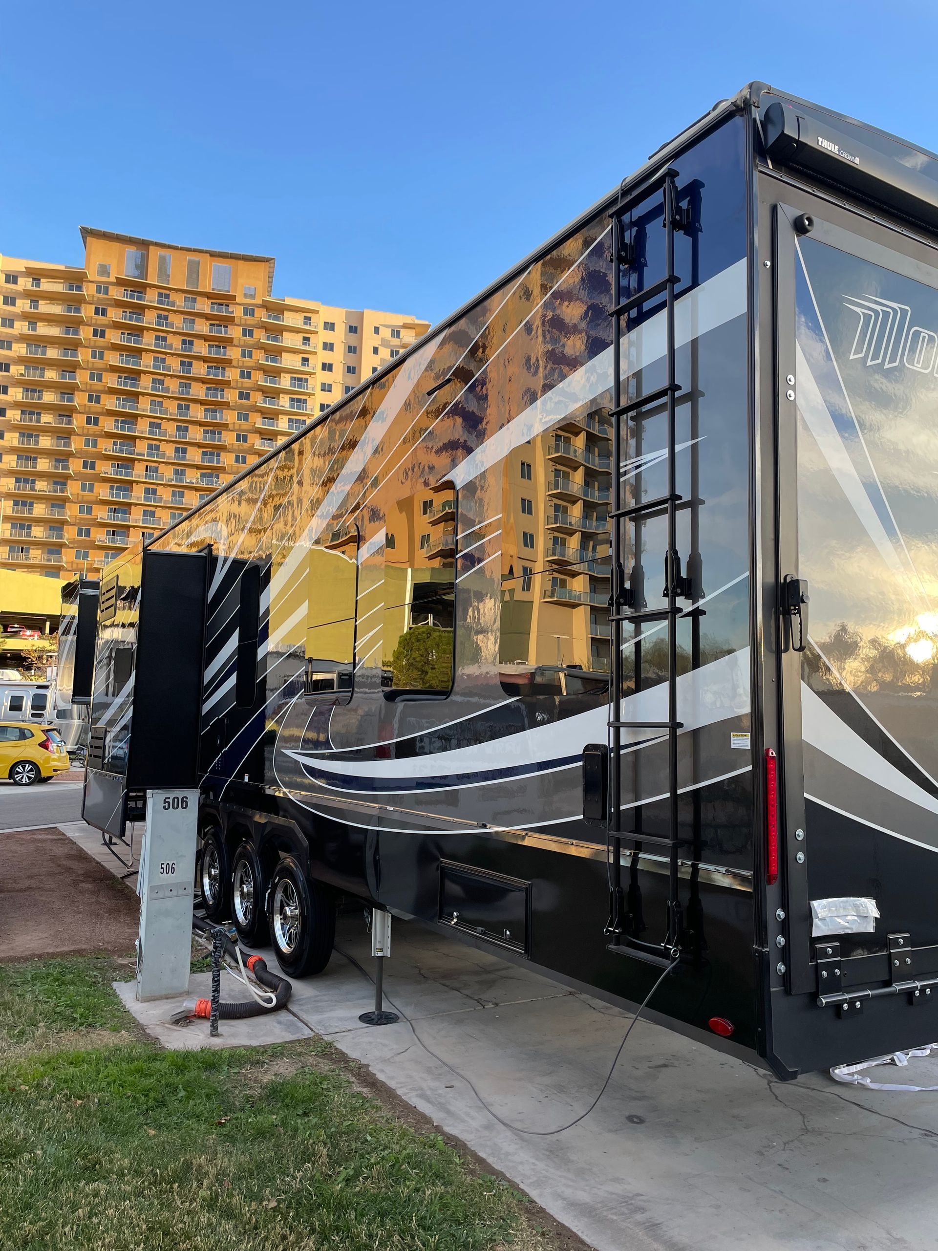 A large rv is parked in front of a tall building.