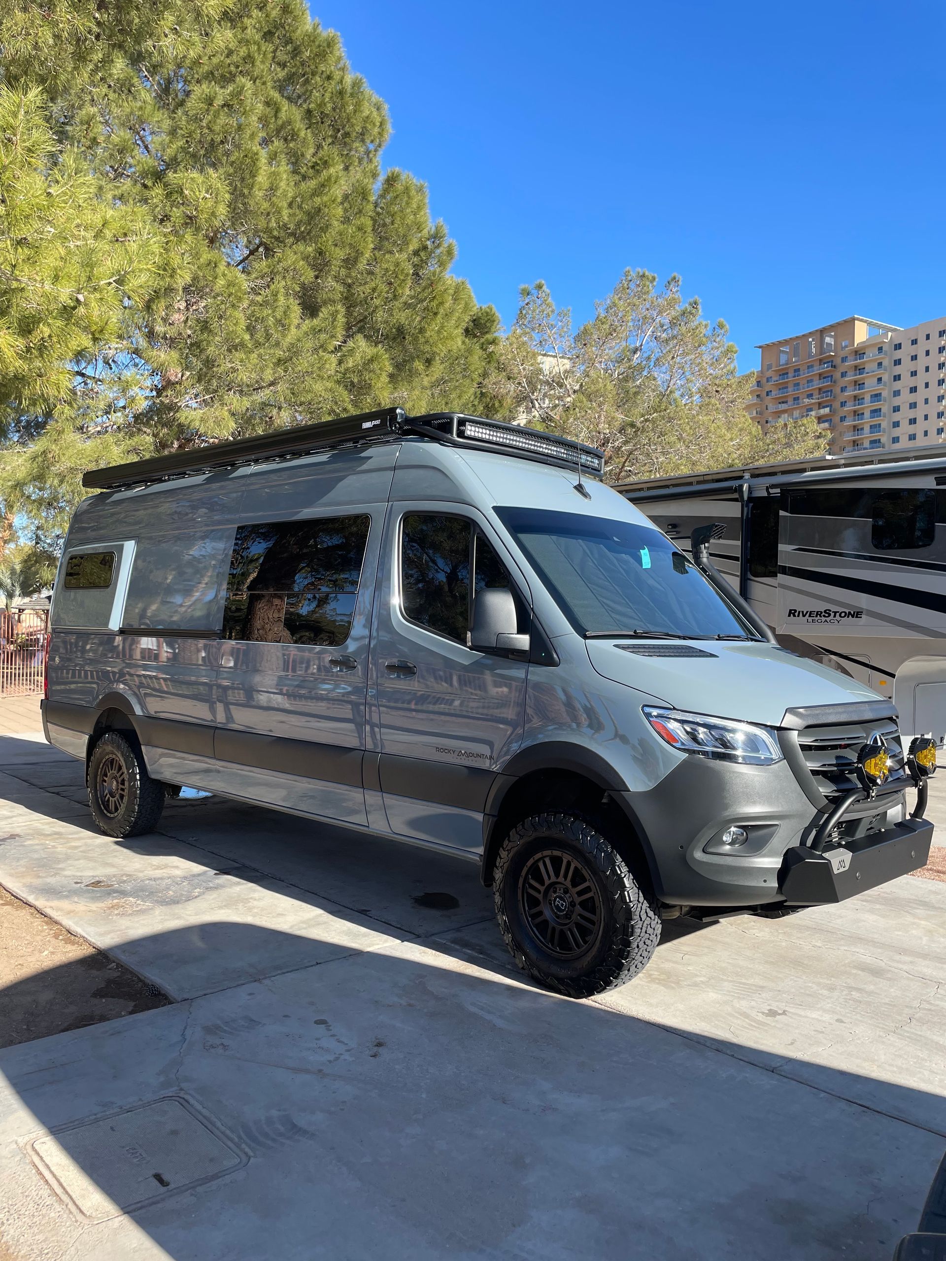 A gray van is parked on the side of the road in a parking lot.