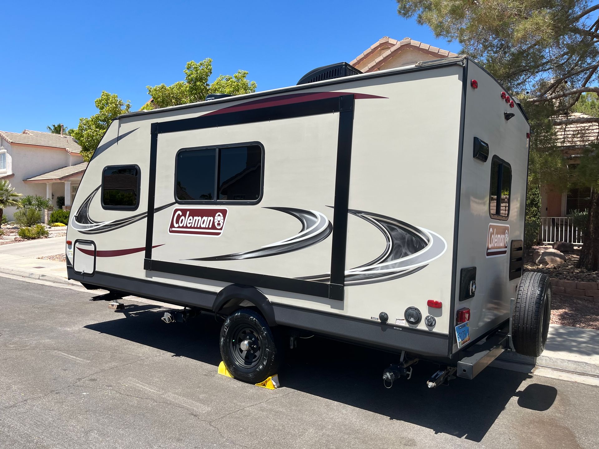 A white coleman trailer is parked on the side of the road.