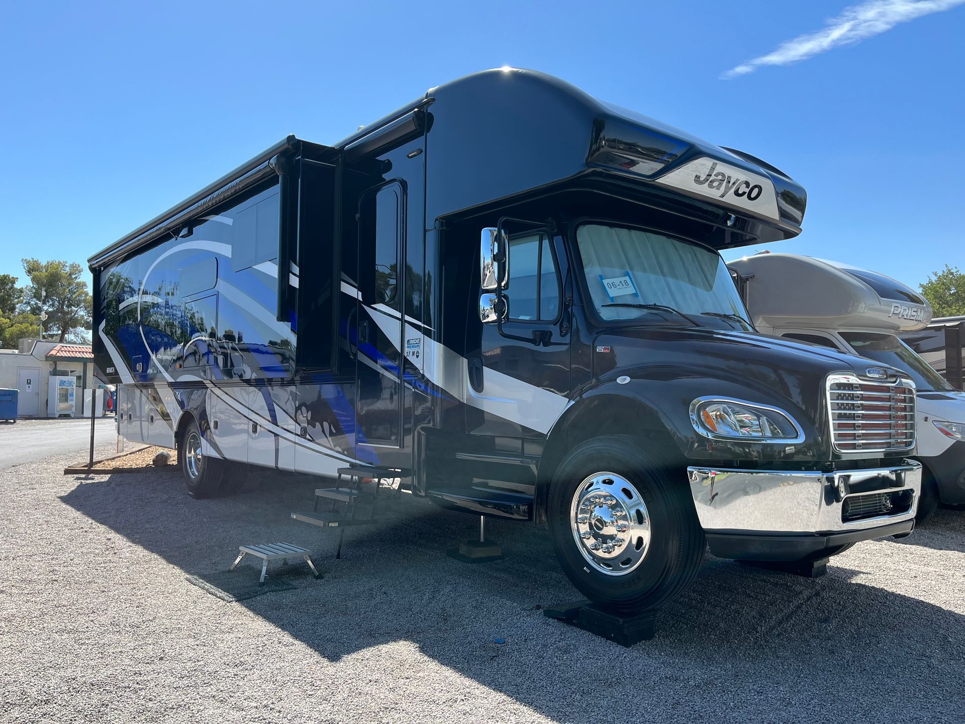 A black and white rv is parked in a gravel lot.