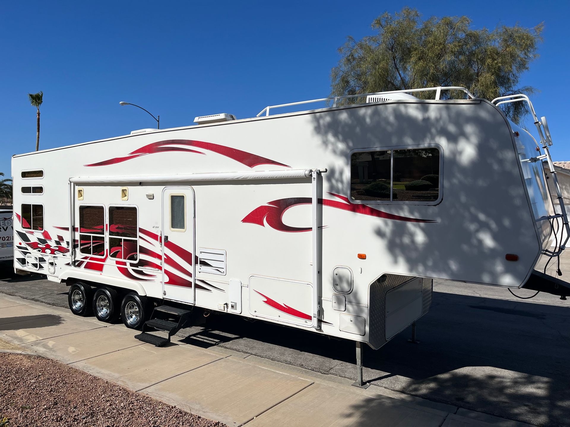 A white and red trailer is parked on the side of the road.