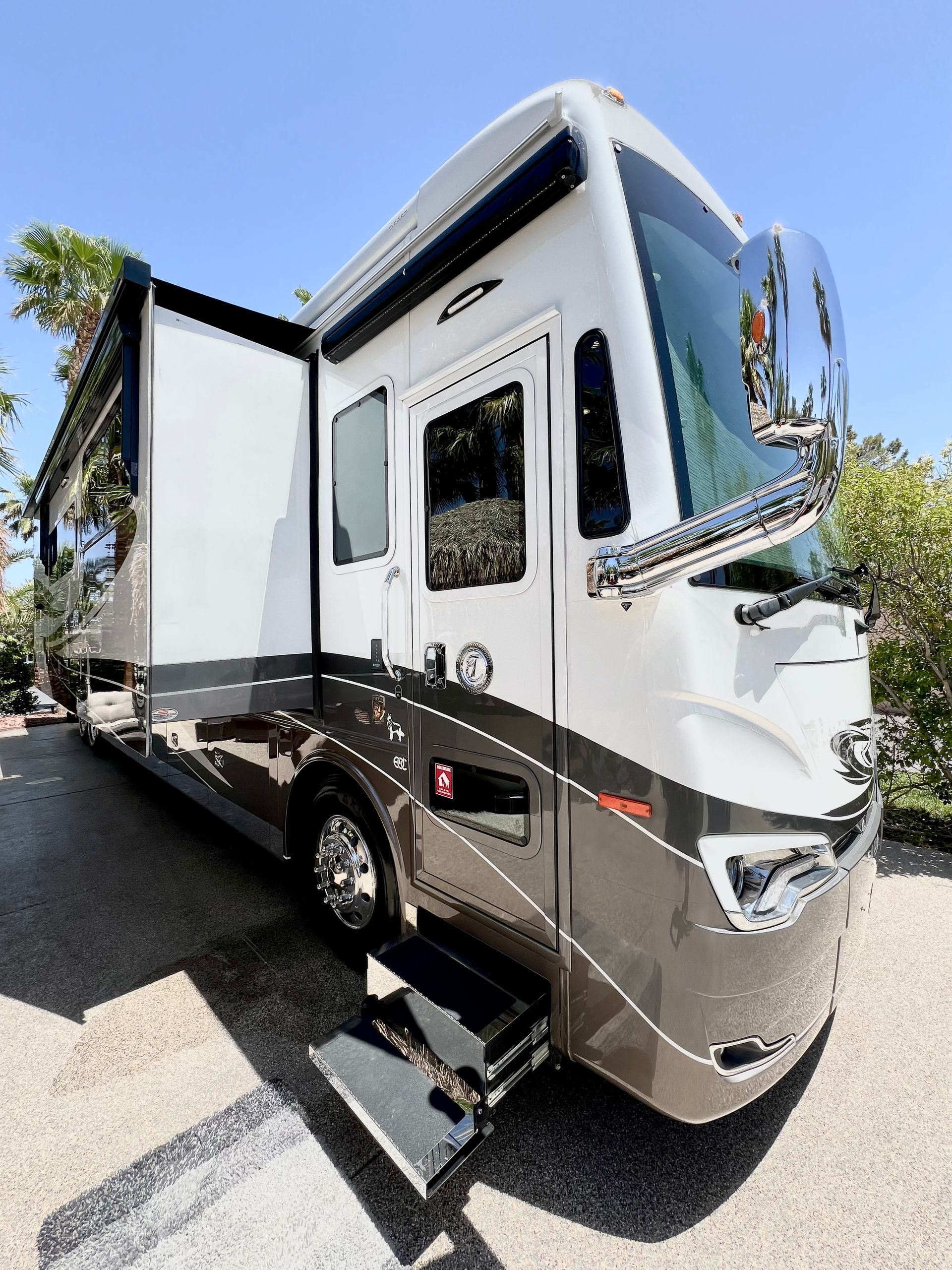 A large white and brown rv is parked in a parking lot.