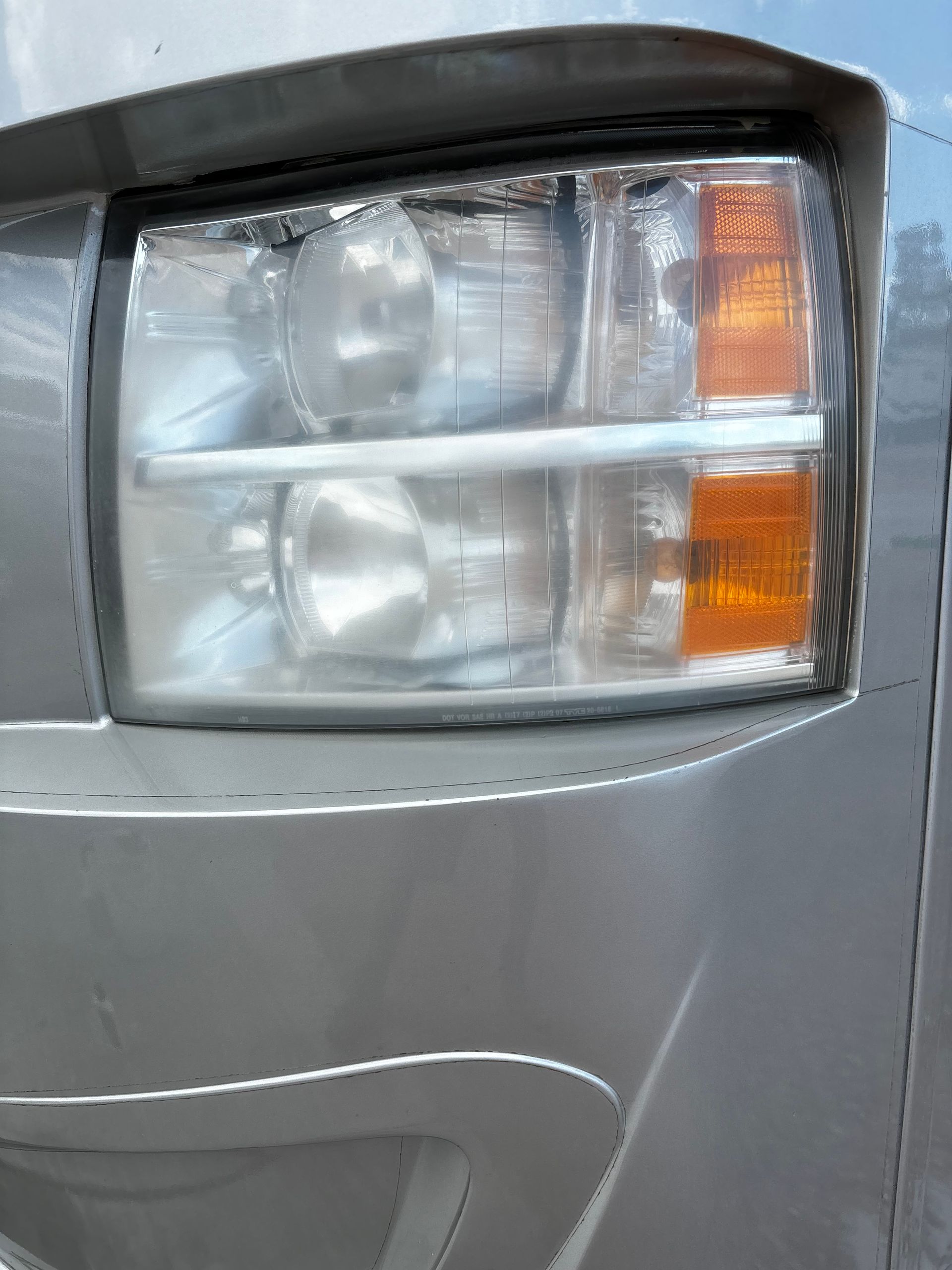 A close up of a silver car 's headlight