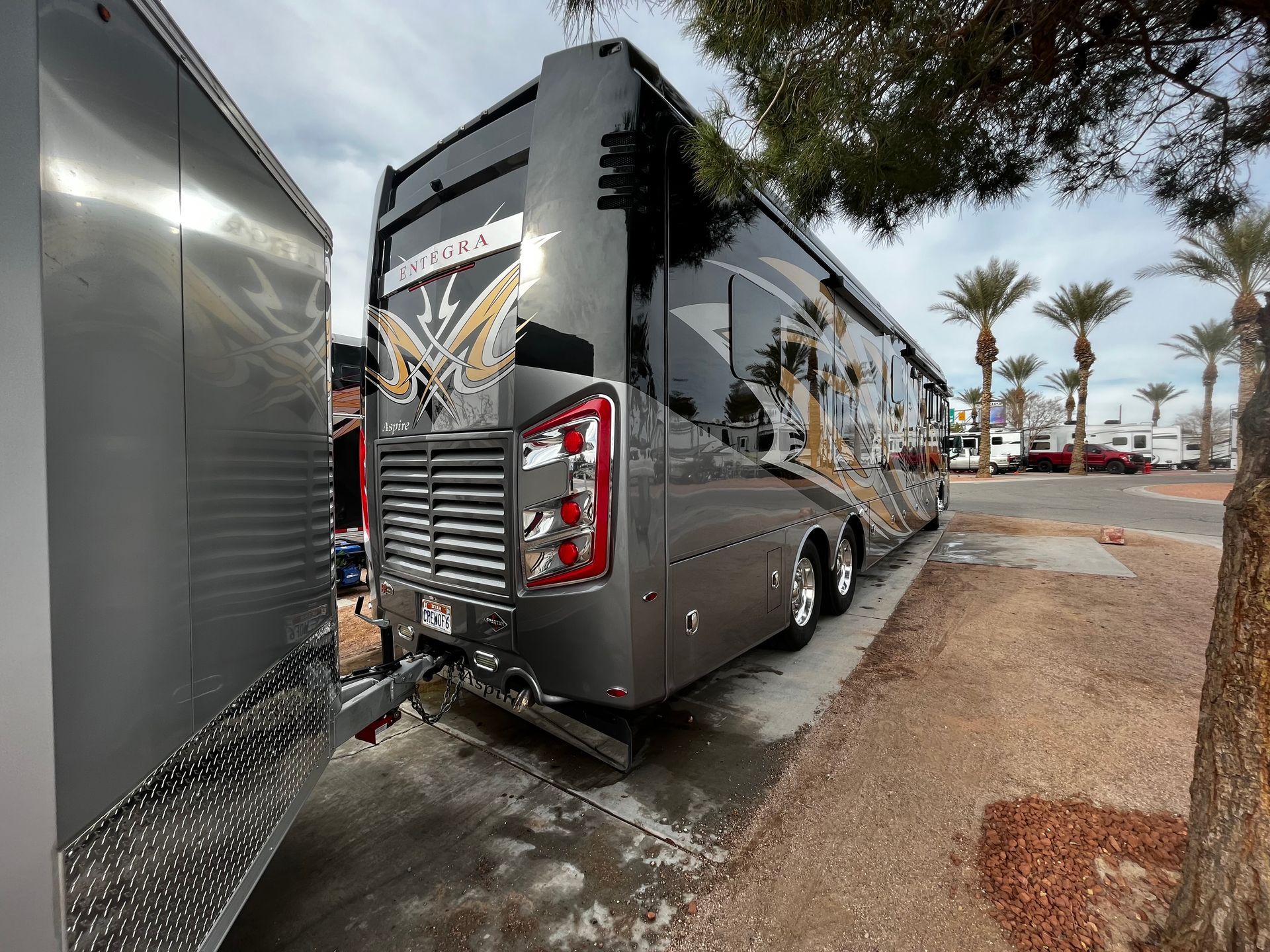 A large rv is parked next to a trailer.