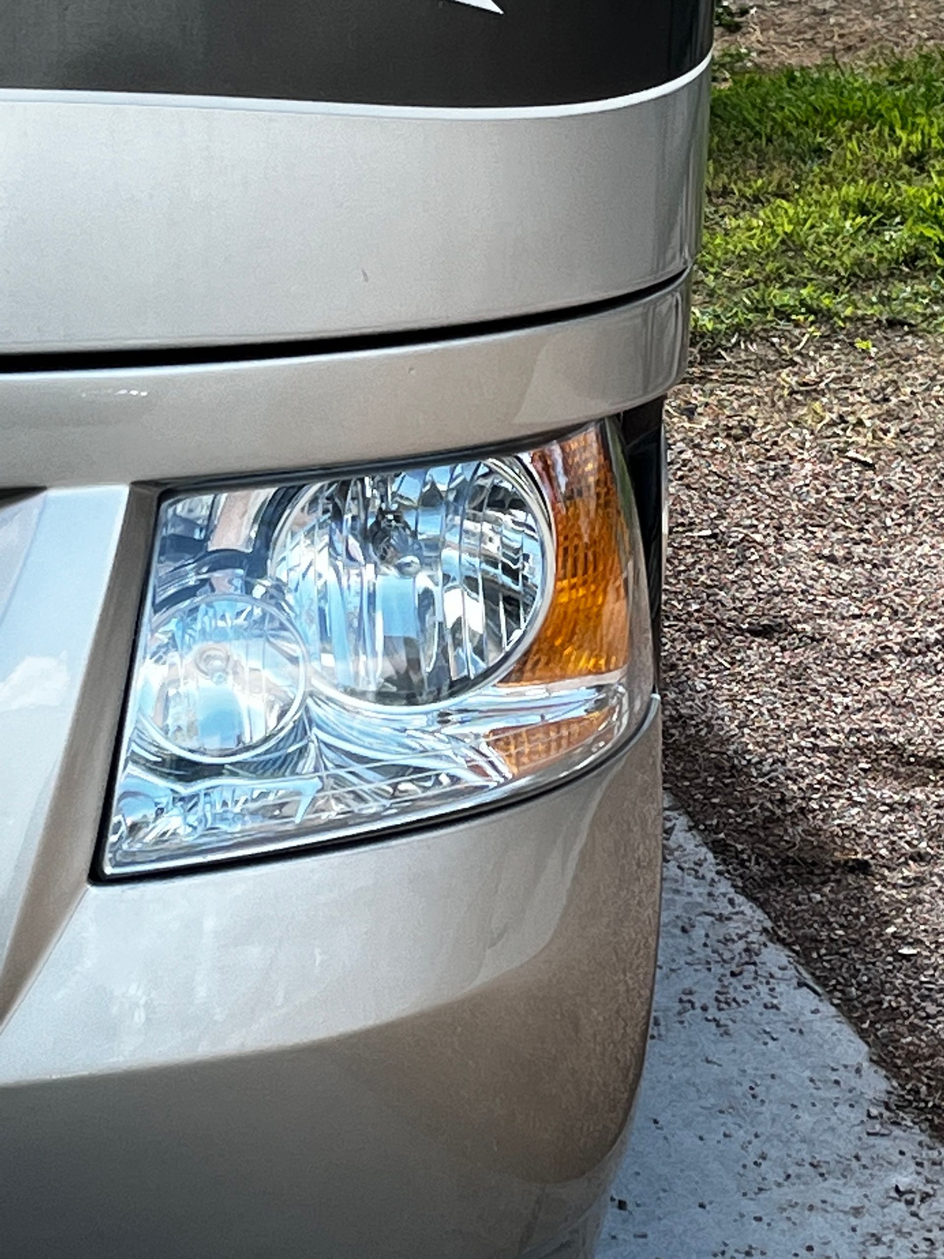 A close up of a car 's headlight on a gravel road