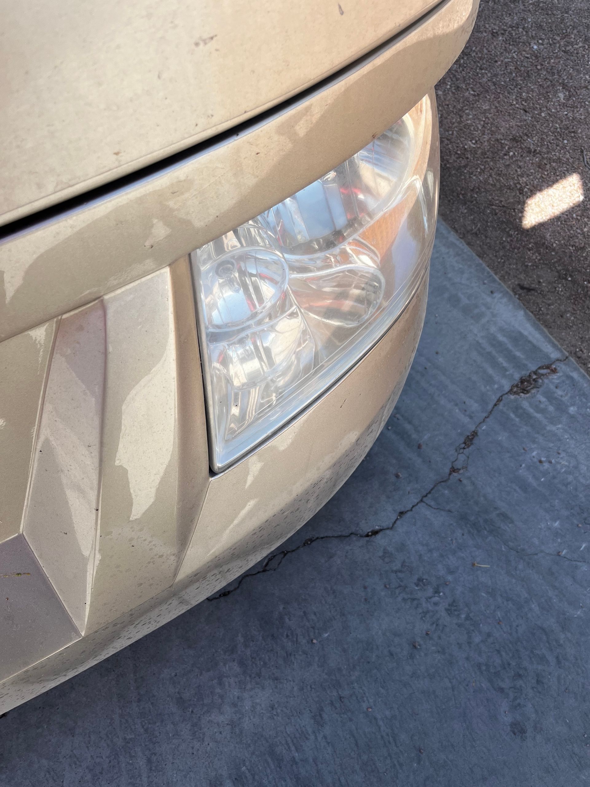 A close up of a car 's headlight on a sidewalk