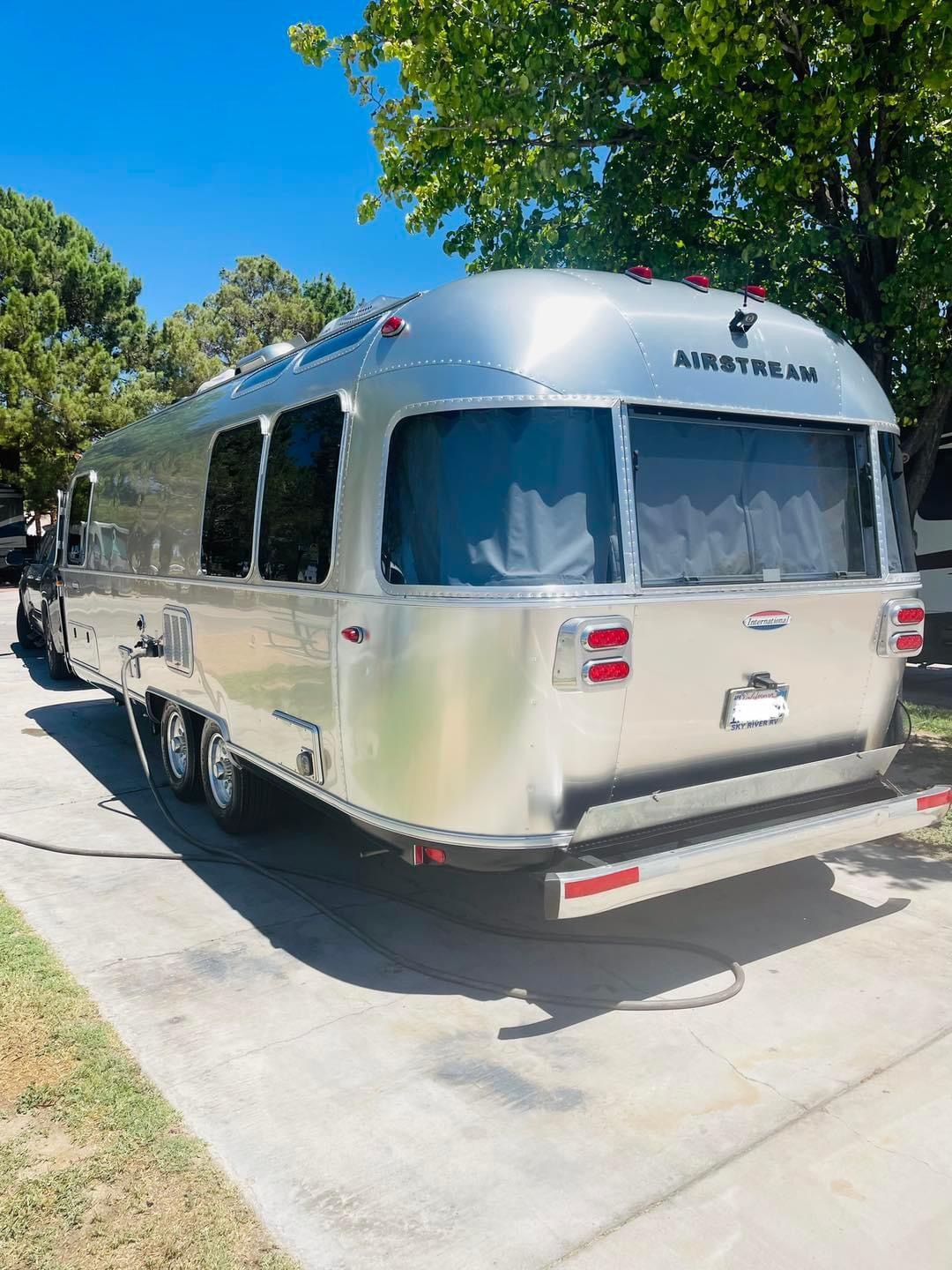A silver airstream trailer is parked on the side of the road.
