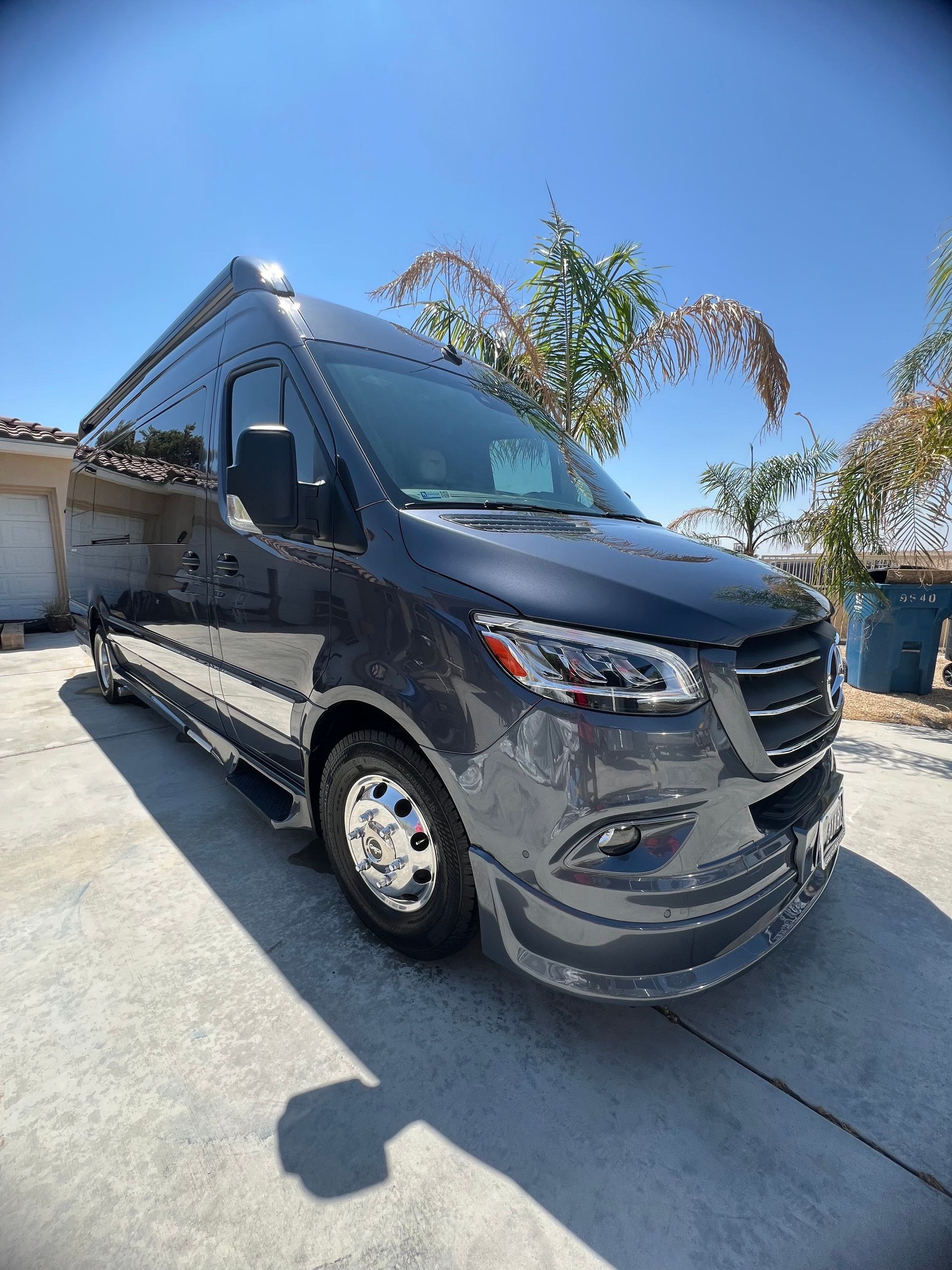 A black van is parked in a driveway in front of a house.