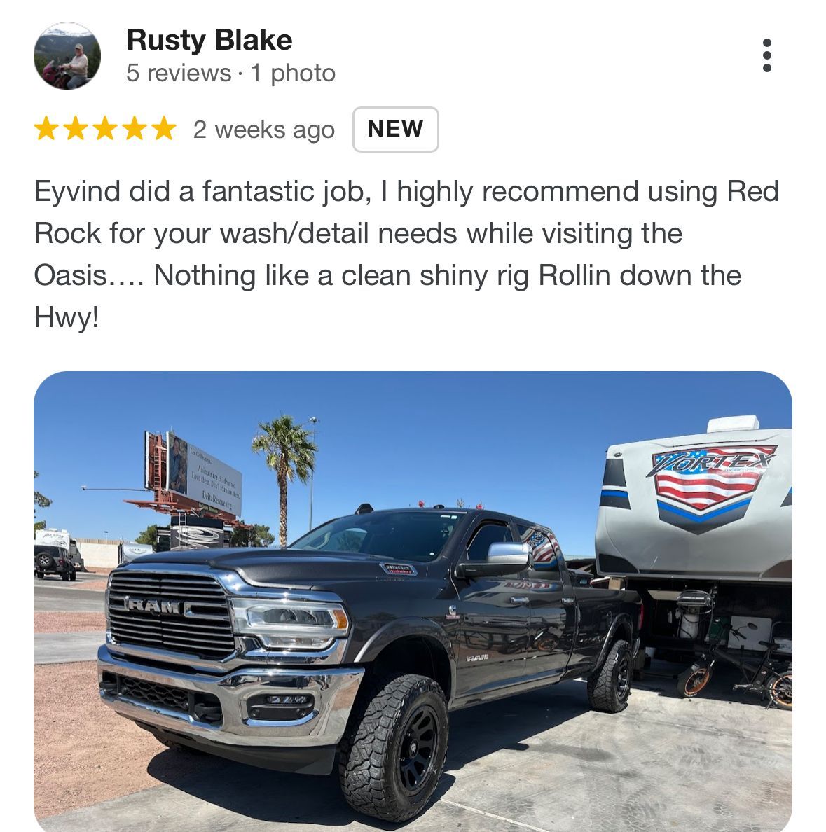 A black truck is parked in a parking lot next to a trailer.