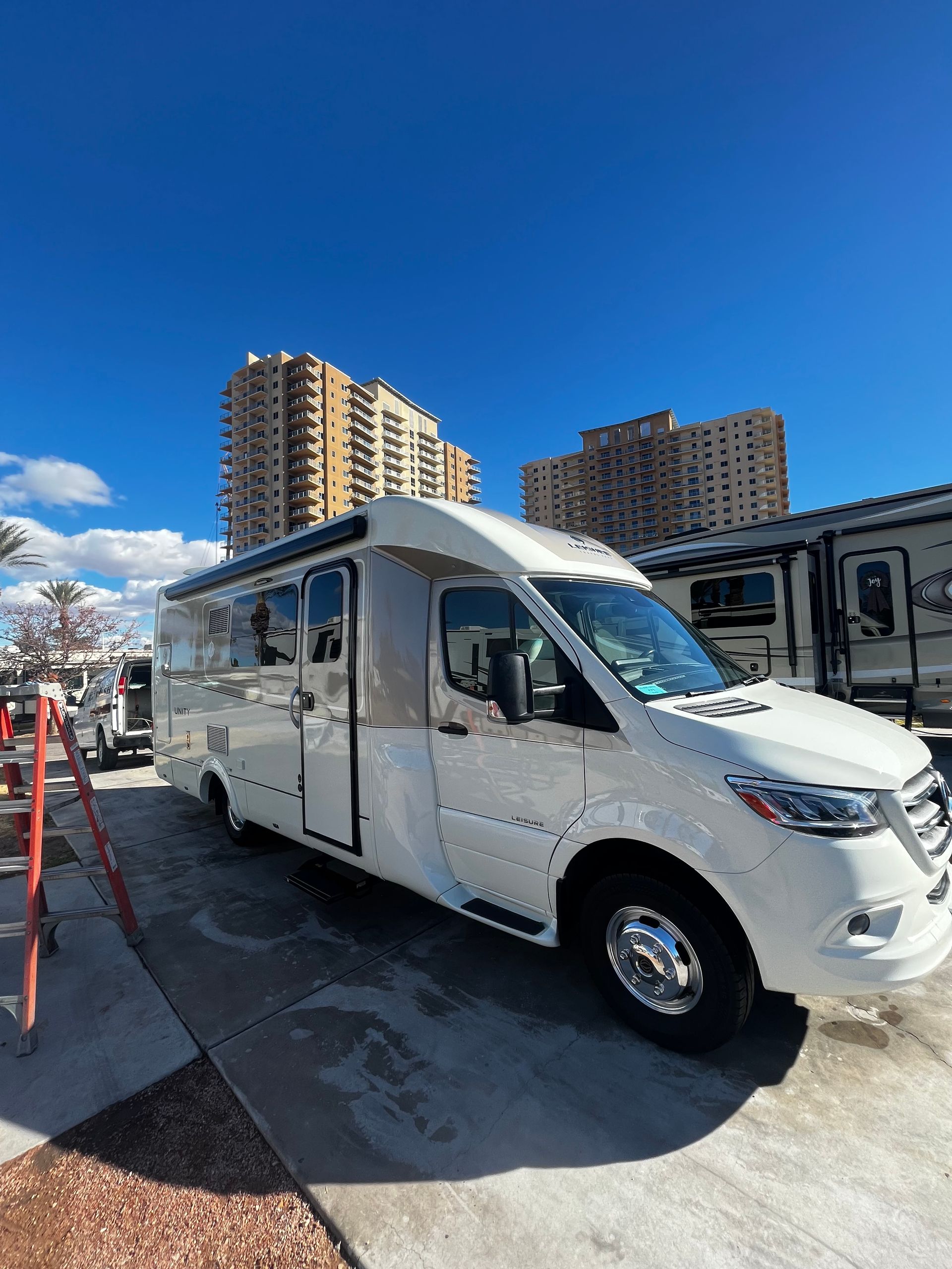 A white van is parked in a parking lot in front of a building.