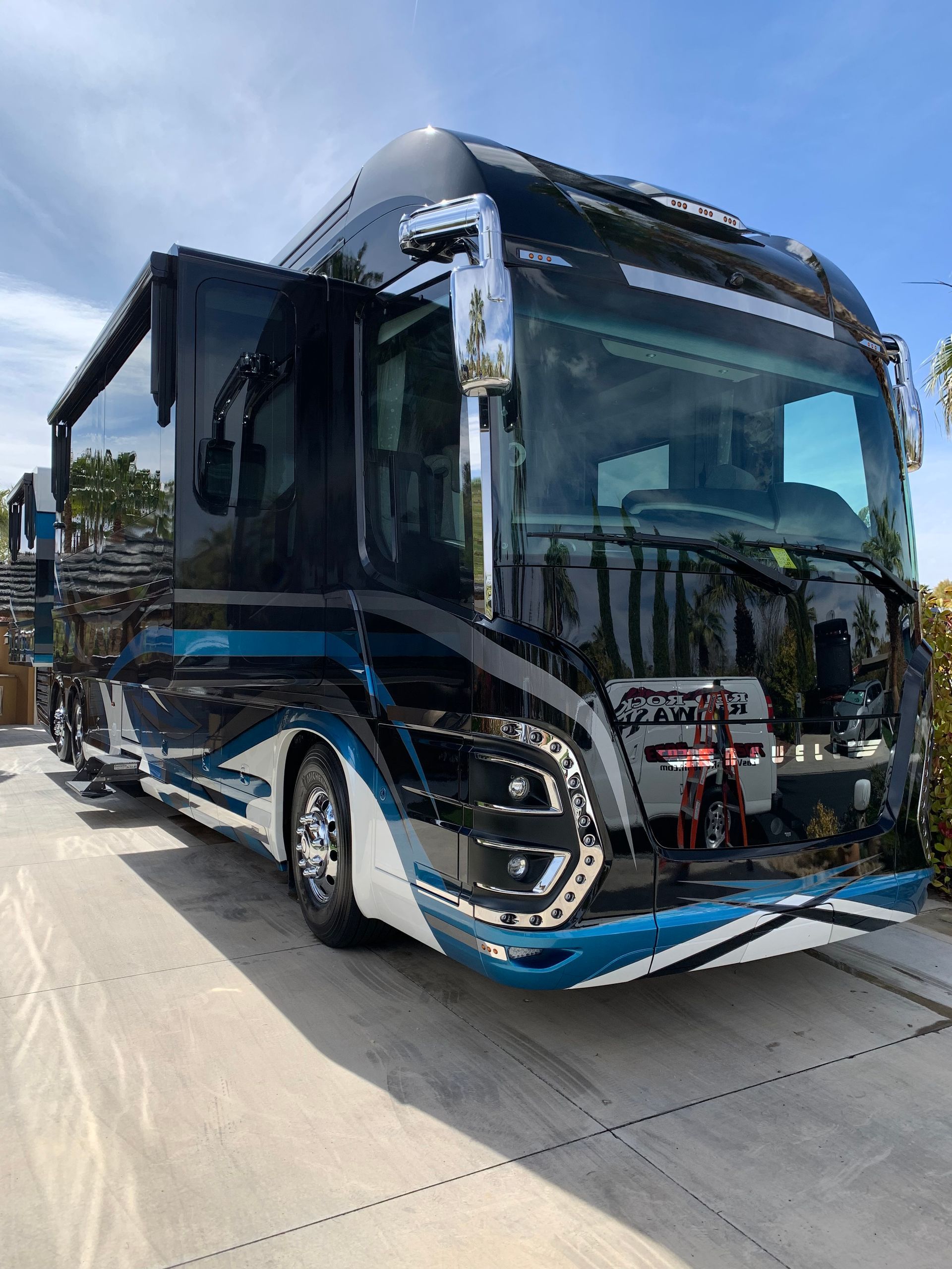 A large black and blue bus is parked in a parking lot.