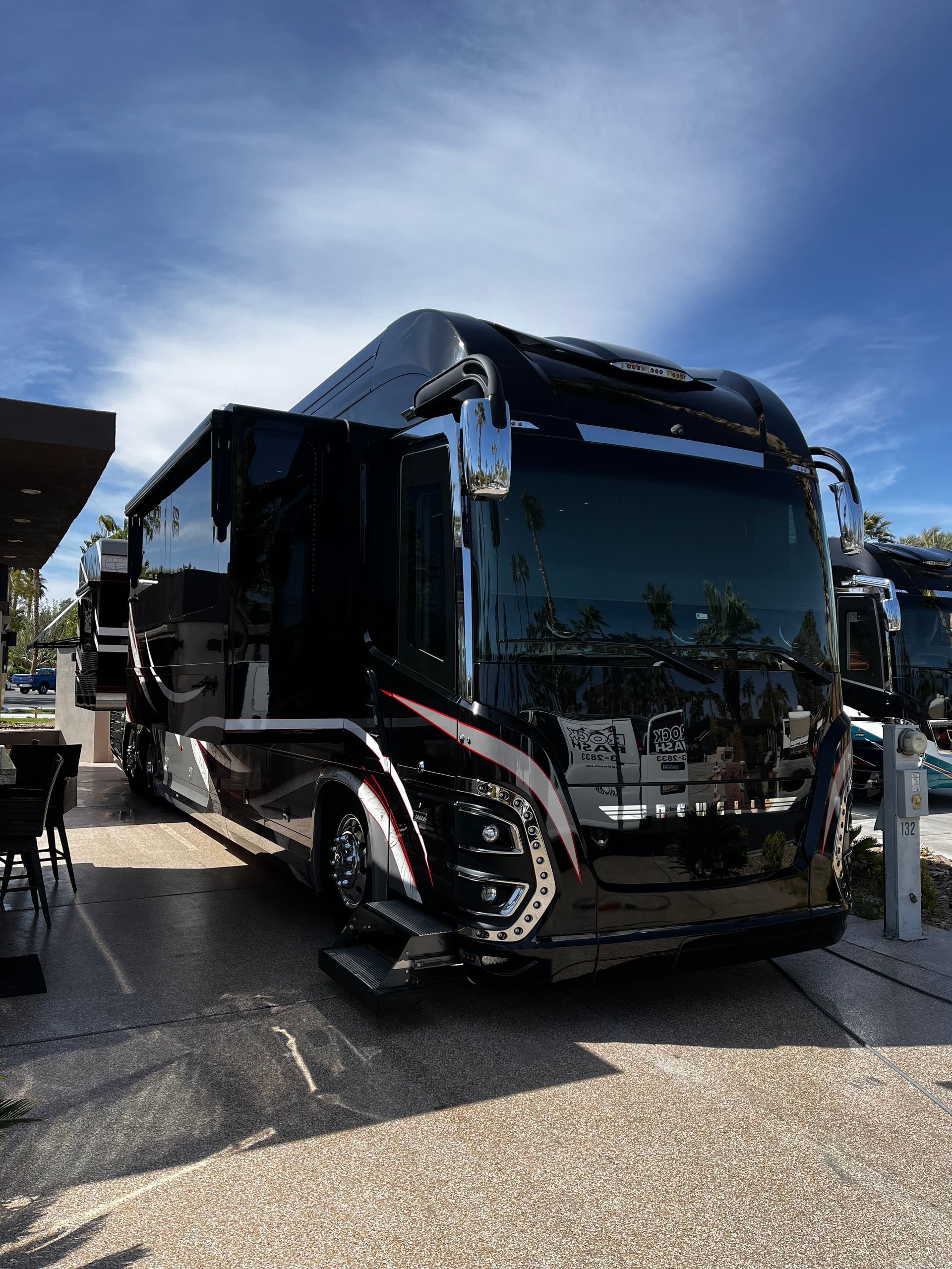 A large black rv is parked in a parking lot.