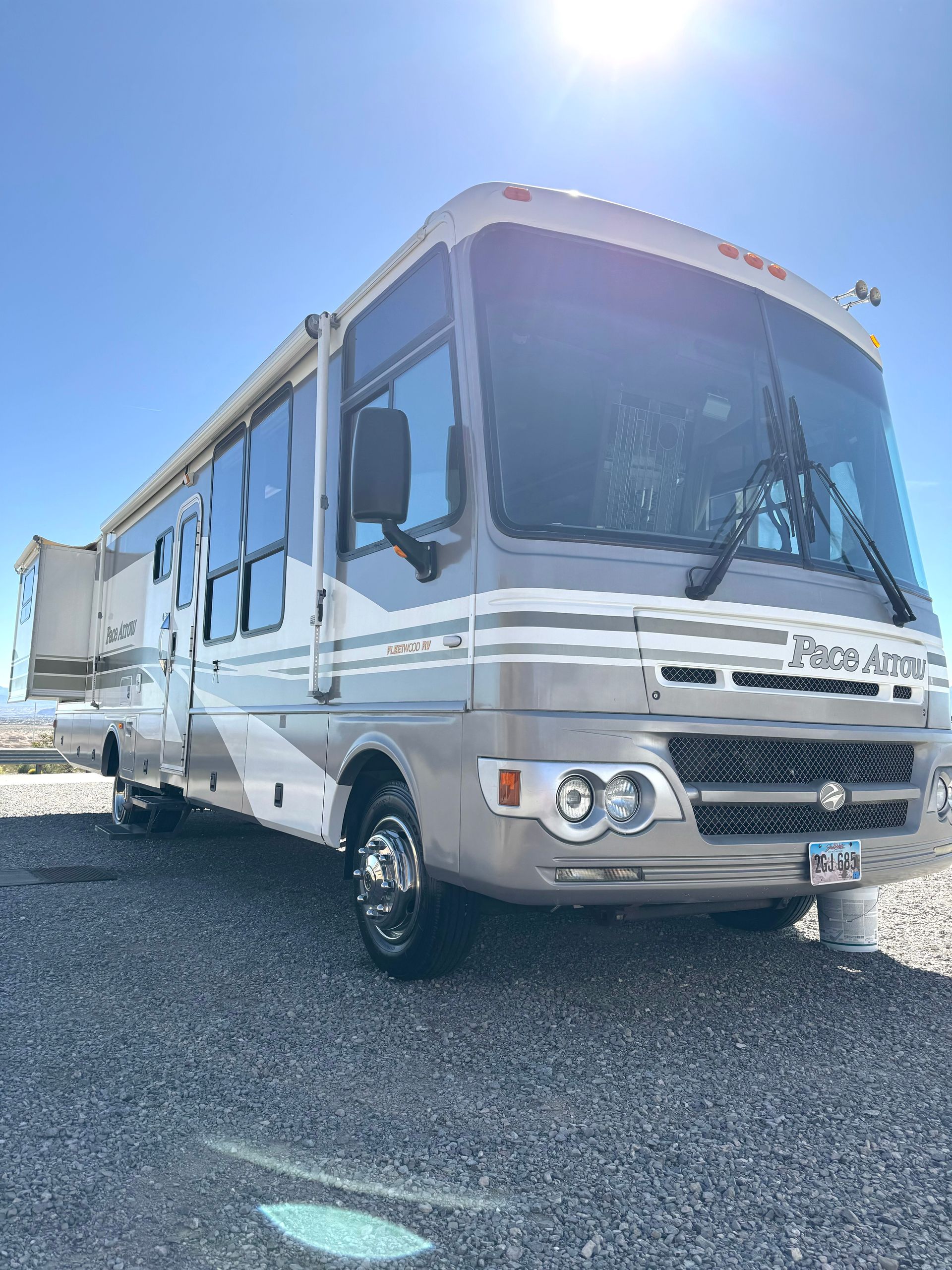A large rv is parked in a gravel lot.