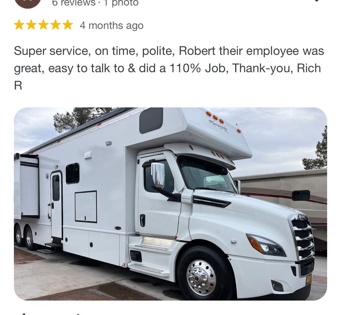 A white truck with a trailer attached to it is parked in a parking lot.