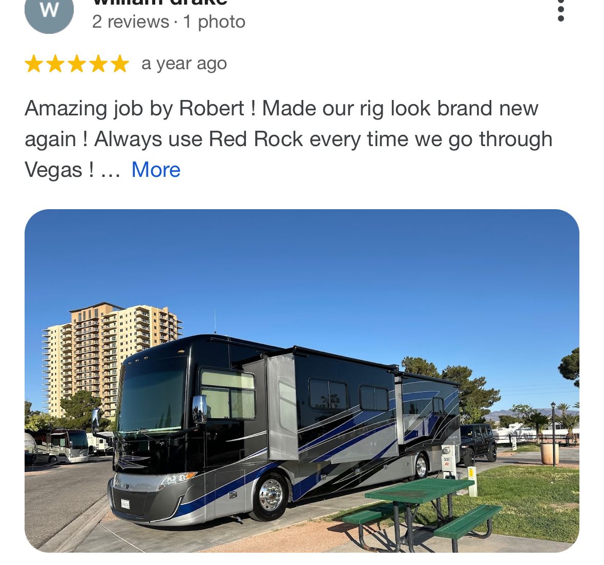 A rv is parked on the side of the road next to a picnic table.