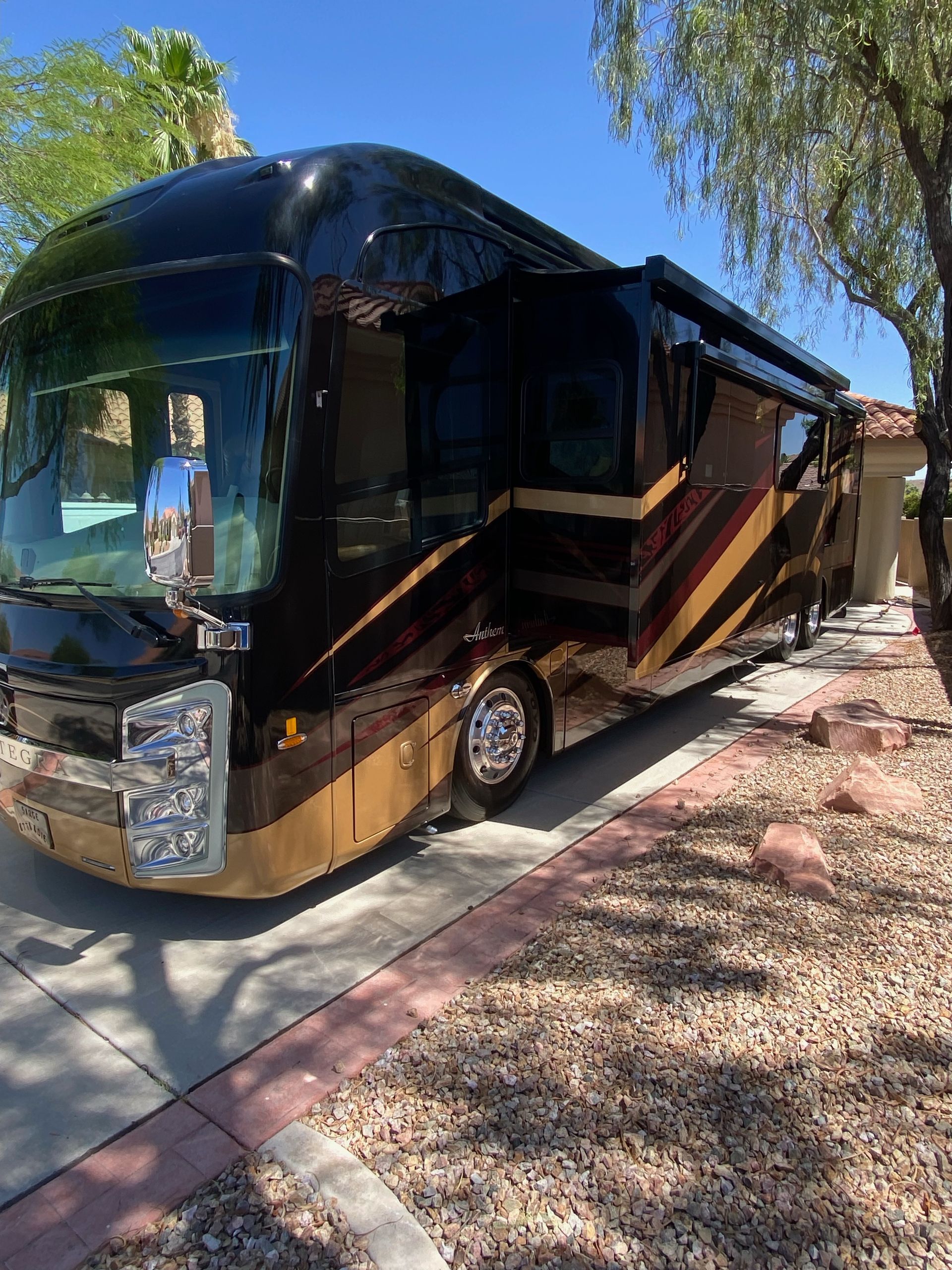 A large black and gold rv is parked on the side of the road.