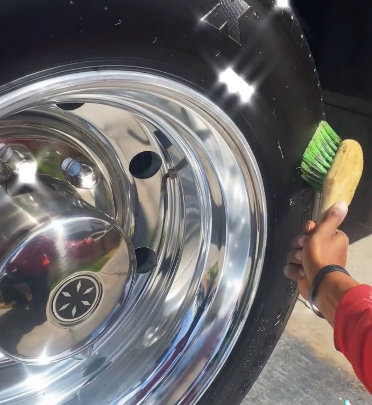 A person is cleaning a tire with a green brush