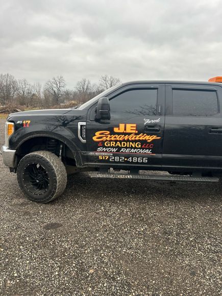 A black tow truck is parked in a gravel lot.