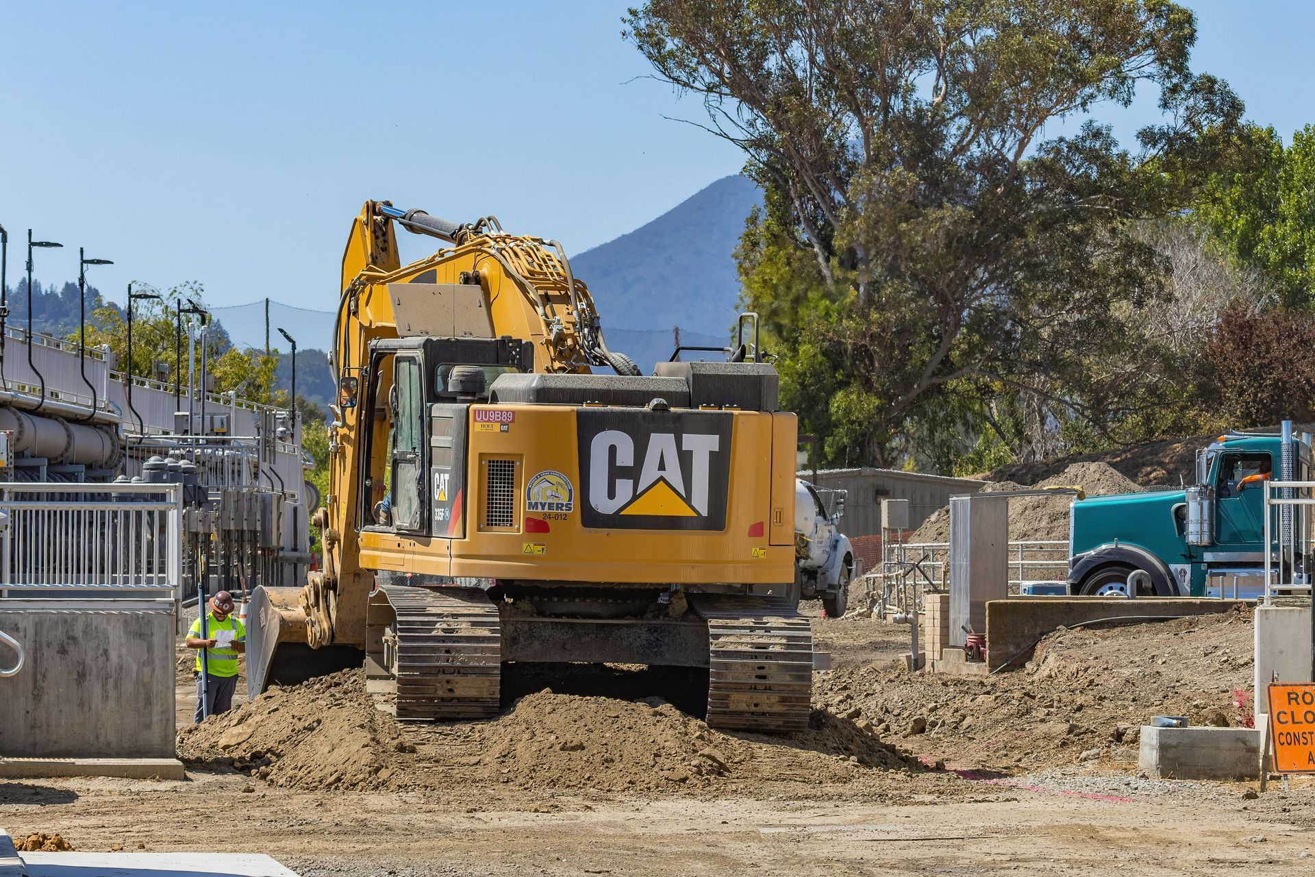 A yellow cat excavator is sitting on top of a pile of dirt.