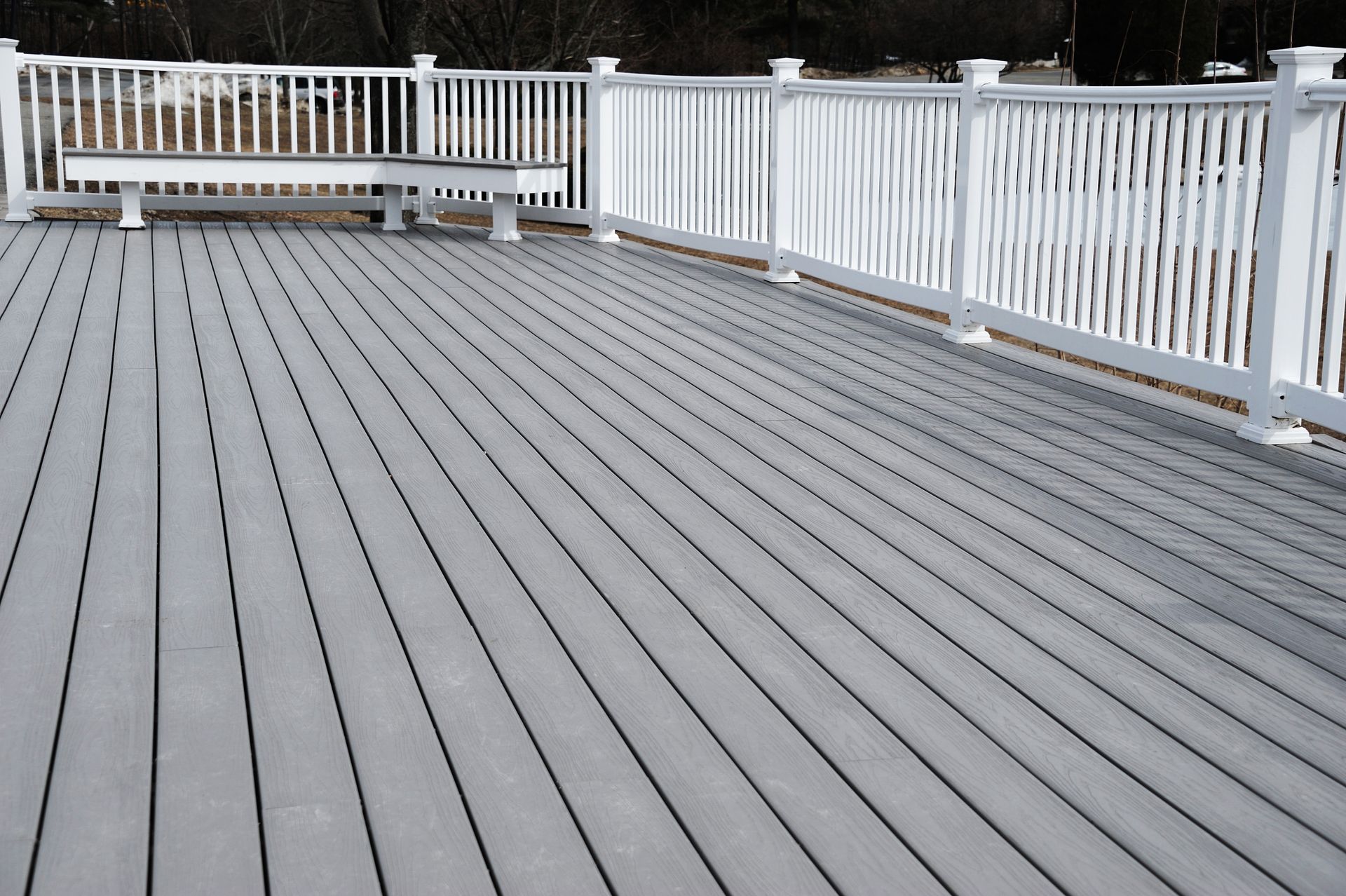A large deck painted grey with white wooden railings.